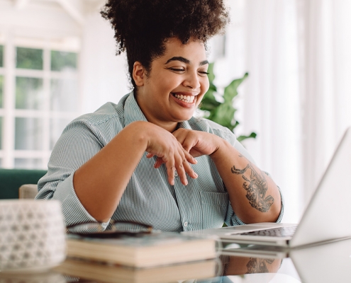 Woman with laptop in living room attending telehealth psychology session