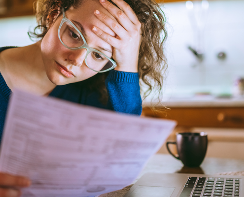 Woman looking at bills rubbing her head