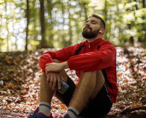 Portrait of relaxed young man with bluetooth headphones in forest